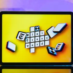 Pomoc krzyżówkowicza z przymrużeniem oka: litery "Mini Cross Word" na ekranie tabletu, jakby ktoś szukał podpowiedzi.