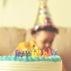 Uroczysty tort z napisami "Happy Day" dla małego solenizanta w kolorowej czapeczce.