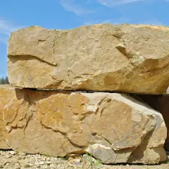 Dwa wielkie bloki piaskowca leżą jeden na drugim na tle błękitnego nieba.