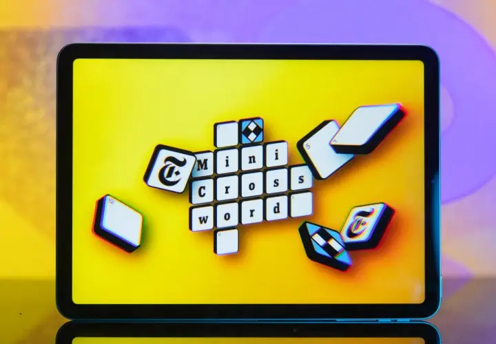 Pomoc krzyżówkowicza z przymrużeniem oka: litery "Mini Cross Word" na ekranie tabletu, jakby ktoś szukał podpowiedzi.