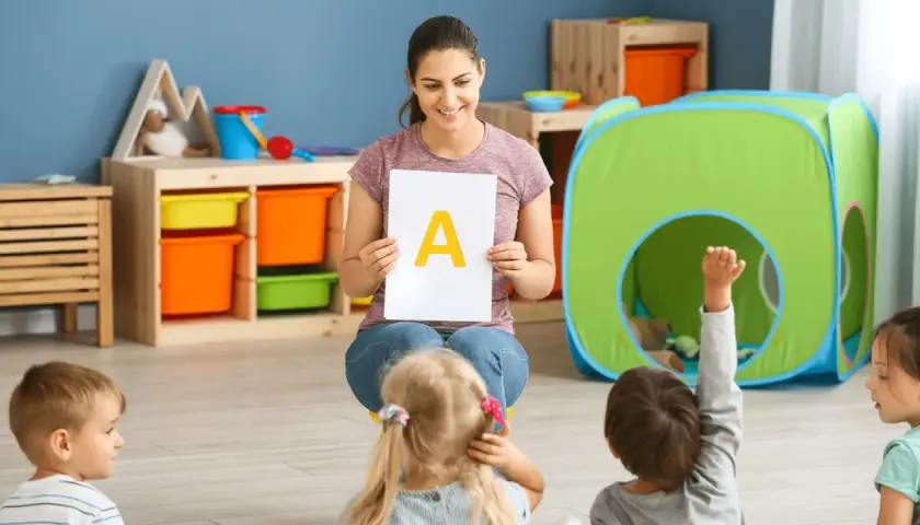 Nauczycielka pokazuje literę "A" dzieciom, wprowadzając je w kolejność wprowadzania liter w przedszkolu.
