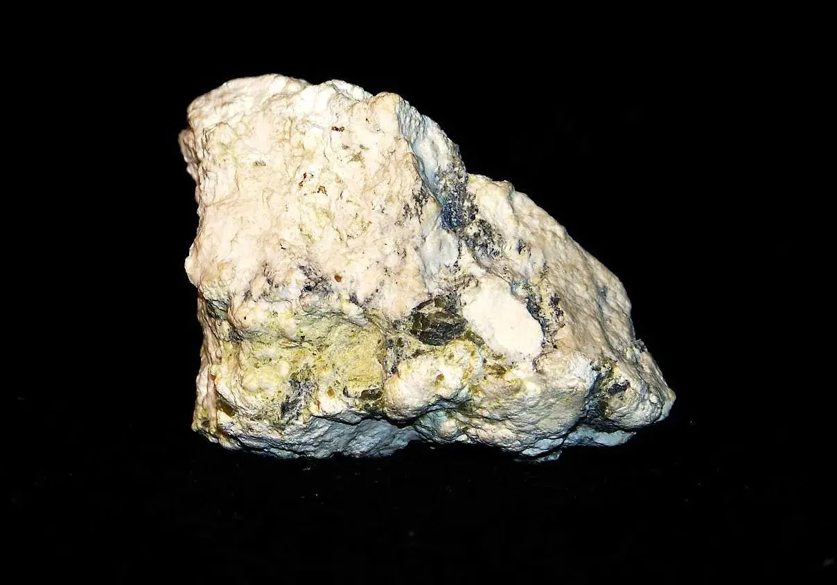 Biały, porowaty minerał z zielonkawo-żółtymi wtrąceniami, przypominający skałę, w której można znaleźć magnetyt.