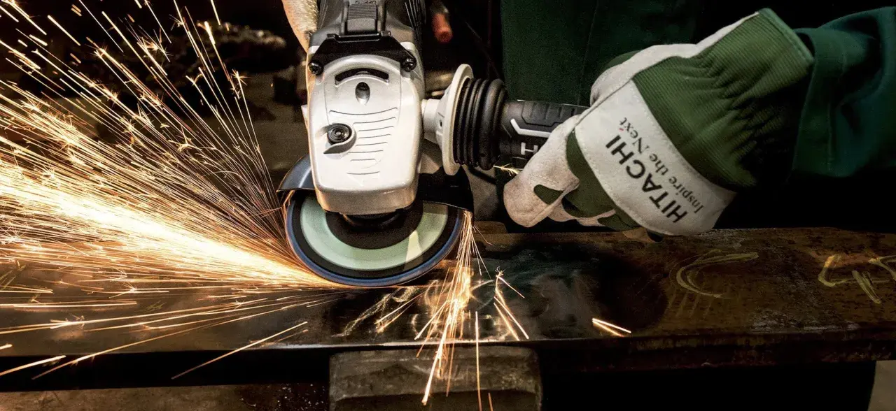 Rękawica Hitachi z tarczą szlifierską generuje iskry, pokazując siłę tarcia statycznego podczas pracy z metalem.