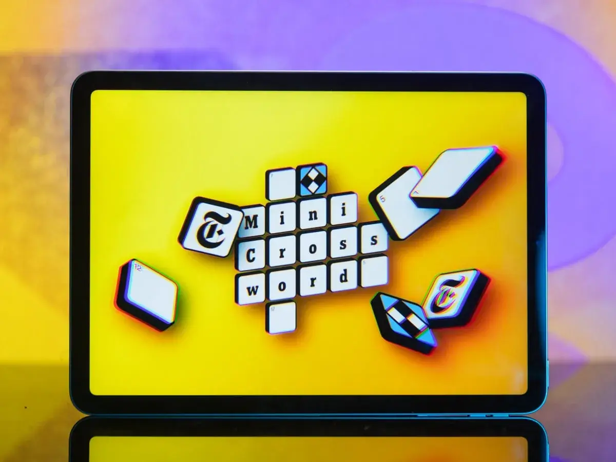 Pomoc krzyżówkowicza z przymrużeniem oka: litery "Mini Cross Word" na ekranie tabletu, jakby ktoś szukał podpowiedzi.
